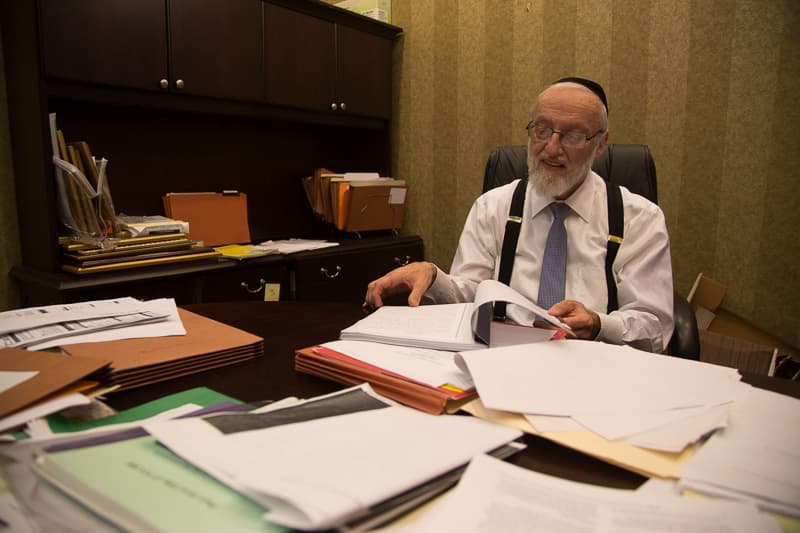 Nachman Caller reviewing documents in his office